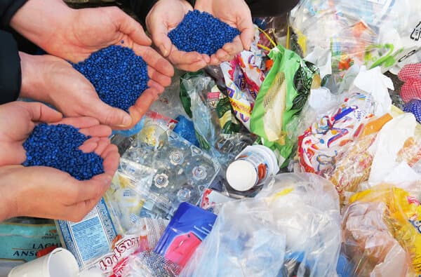 Plastik_Granulat-in-Haenden-vor-Abfall